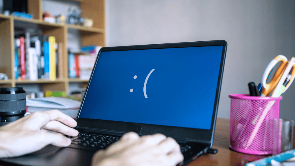 laptop with a blue screen with a sad face on it