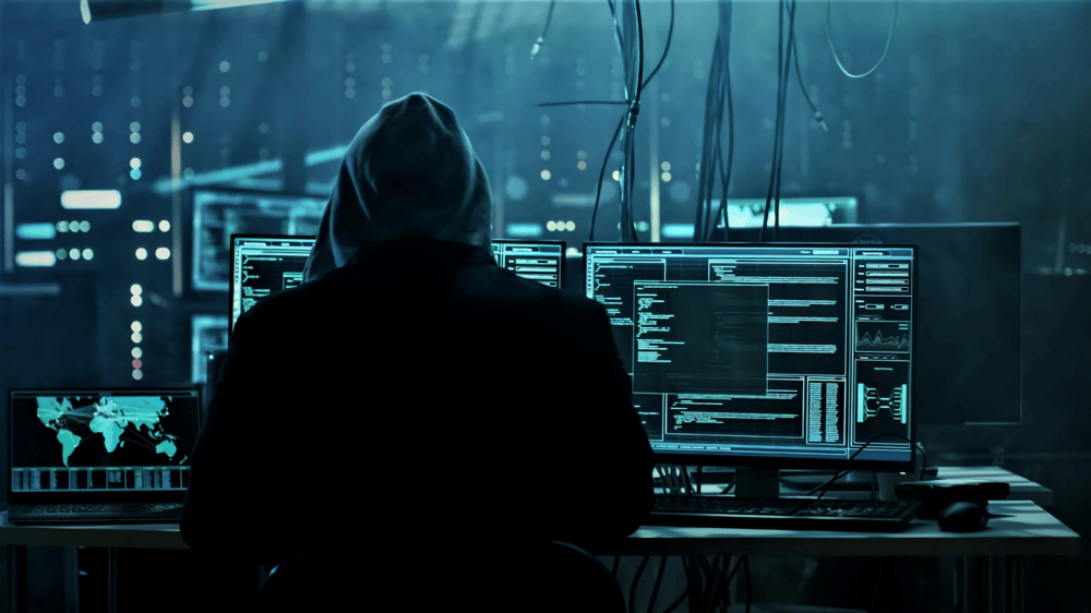 hacker looking at computer screens at night