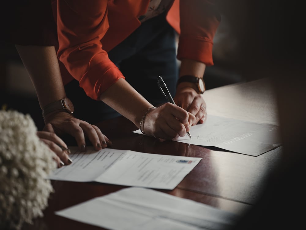 Business associates signing a paper contract at a wood table