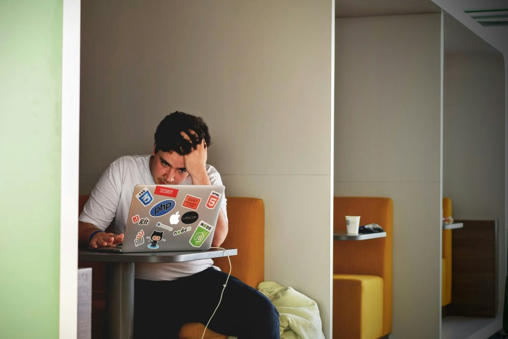 frustrated looking man sitting with his laptop